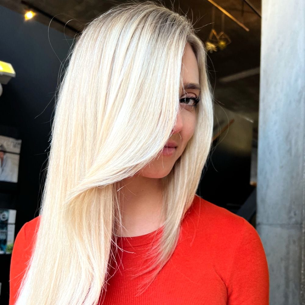 Sleek platinum blonde hair partly covering a woman’s face, worn with a red top